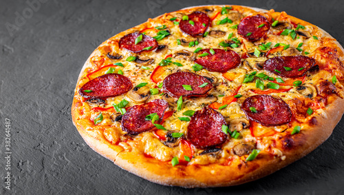 Pepperoni Pizza with Mozzarella cheese, salami, pepper, Spices and mushrooms. Italian pizza on Dark grey black slate background