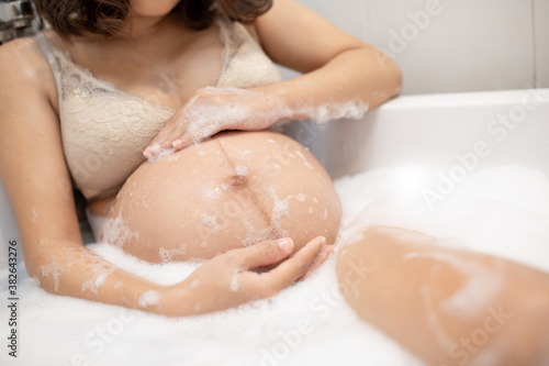 A Pregnant Woman in a bathtub with Soap bubble.Concept of pregnancy  expecting a baby  love  care.pregnancy  motherhood  people and expectation. 