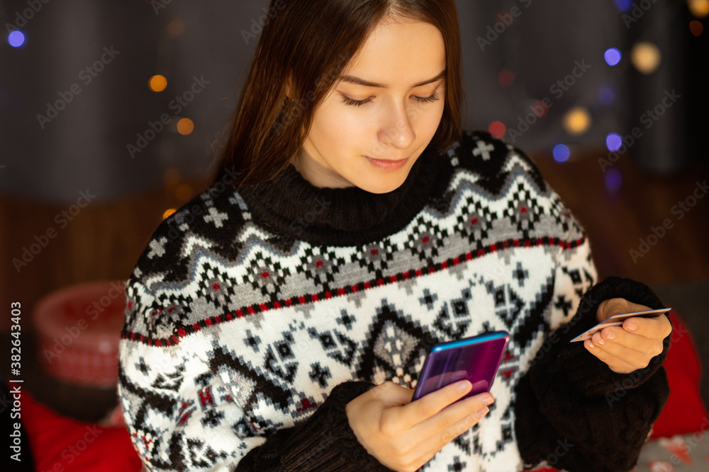 Young woman preparing for christmas, shopping online from credit card, choosing gifts on sale