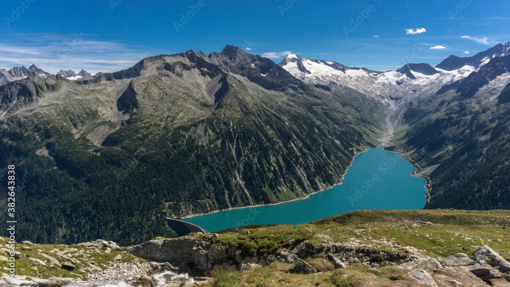 Obraz premium Panorama Alpine lake with dam in stunning mountain range
