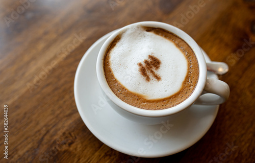 The Cup of Latte or Cappuccino Coffee with Milk on wooden table.