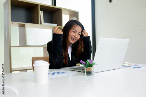 Asian businesswoman cheering while looking at laptop on the desk in the office. Business concept.