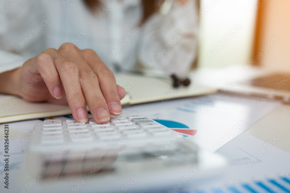 Businesswoman using calculator blurred background.Savings, finances, and economy concept through a laptop. Businesswoman using calculator blurred background.Savings, finances, and economy concept through a laptop.
