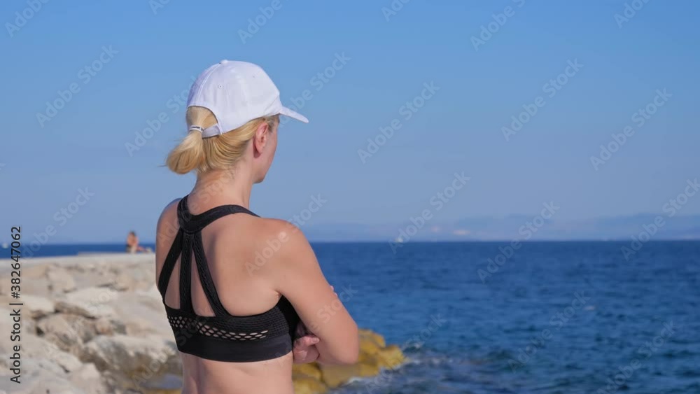 A young woman in sportswear stands on the rocks by the sea and looks out to sea. A beautiful summer morning on the Adriatic Sea.
A young woman in sportswear stands on the rocks by the sea and looks out to sea. A beautiful summer morning on the Adriatic Sea.