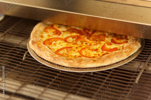 Freshly baked pizza comes out of modern oven