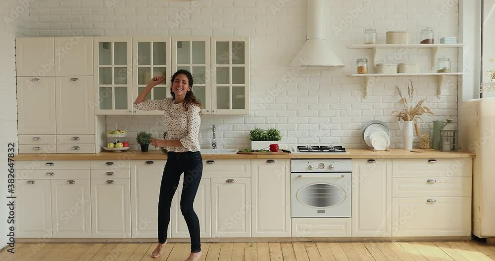 Wide full-length wide view in modern spacious kitchen lively housewife singing feels happy, dancing barefoot on warm floor with underfloor heating system. Hobby and luxury home owner free time concept Wide full-length wide view in modern spacious kitchen lively housewife singing feels happy, dancing barefoot on warm floor with underfloor heating system. Hobby and luxury home owner free time concept