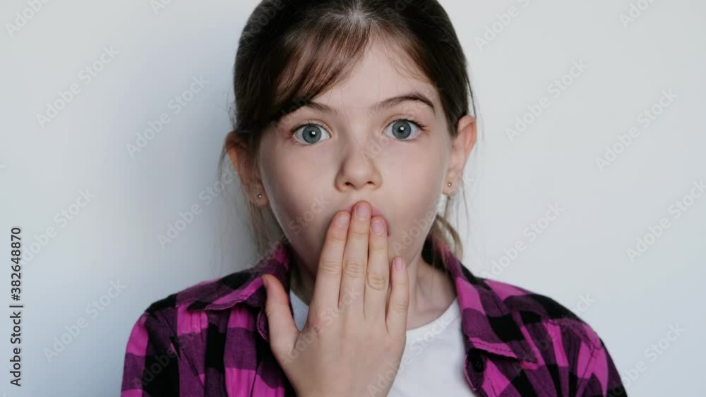 little / young girl in a pink plaid shirt with big blue eyes is surprised, opened her mouth in surprise. On white background. little / young girl in a pink plaid shirt with big blue eyes is surprised, opened her mouth in surprise. On white background.