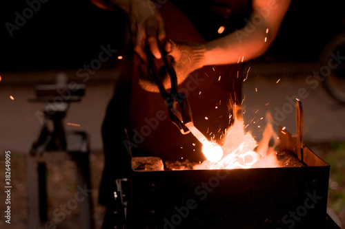 Foto a furnace burning with a bright flame and the hands of a blacksmith with tongs