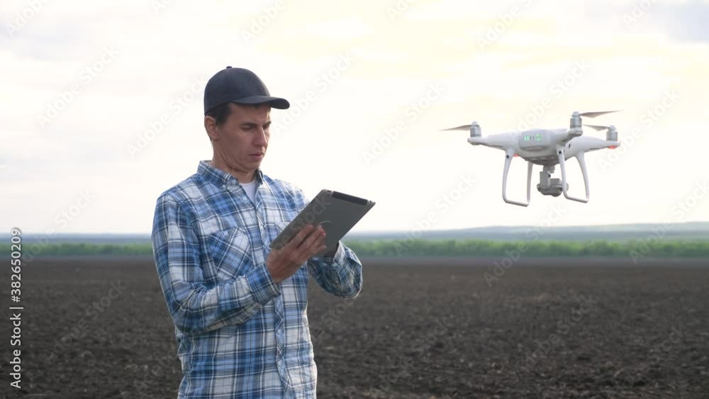 smart farming tech agriculture farming. man farmer engineer studies a farmland in black mud dirt field using a technology quadcopter. male red worker neck works in a green in lifestyle field of corn smart farming tech agriculture farming. man farmer engineer studies a farmland in black mud dirt field using a technology quadcopter. male red worker neck works in a green in lifestyle field of corn