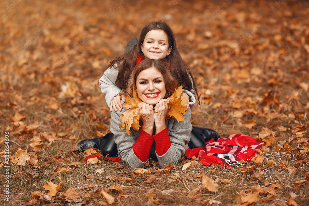 Fashionable mother with daughter. Family in a autumn park. Little girl in a gray coat Fashionable mother with daughter. Family in a autumn park. Little girl in a gray coat