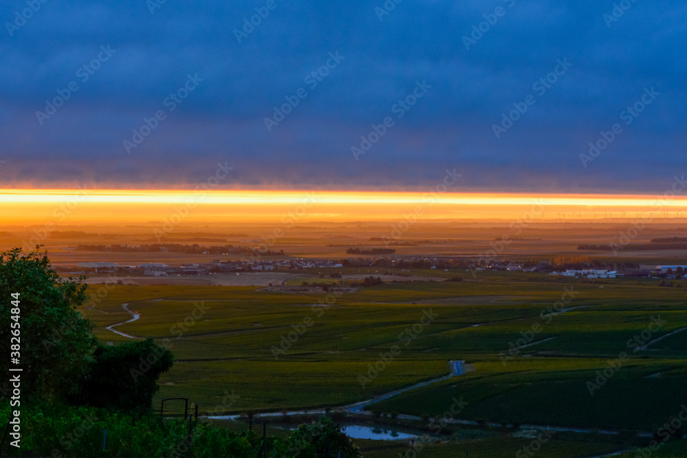Obraz premium Amazing sunrise on rainy day over green grand cru vineyards near Epernay, region Champagne, France. Cultivation of white chardonnay wine grape on chalky soils of Cote des Blancs.