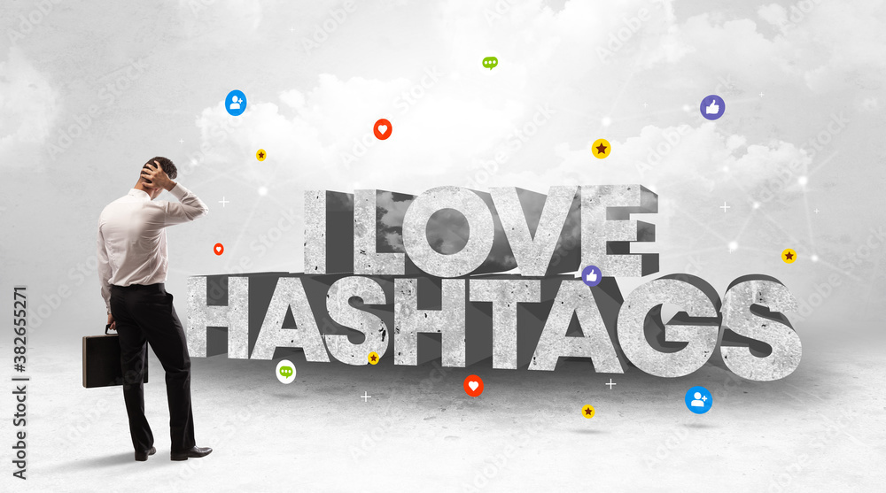 Young businessman standing in front of I LOVE HASHTAGS inscription, social media concept Young businessman standing in front of I LOVE HASHTAGS inscription, social media concept
