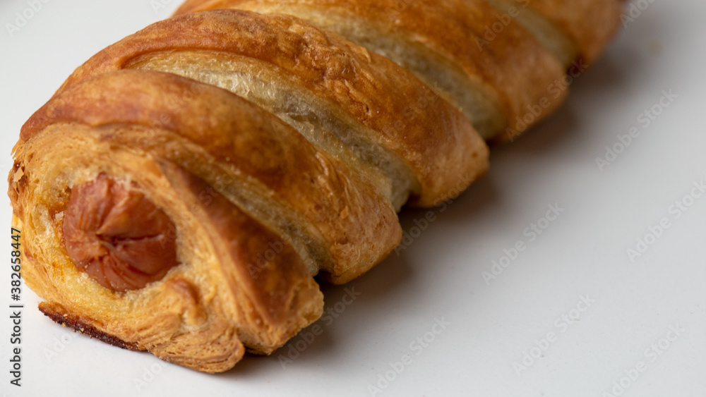 close up of a sausage roll on white background 