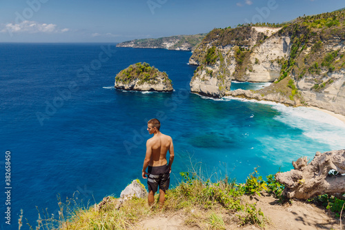 Traveller young man stay near Atuh beach and looks to ocean on Nusa Penida, Indonesia.