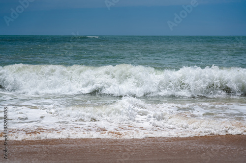 Seascape of strongly wave flowing current with clearly blue sky background during day time. Selective focus at the splashing water on the front.