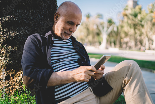 Smiling elderly man messaging on smartphone in park