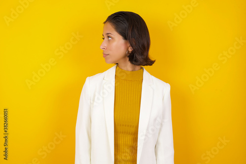 Profile of serious woman with healthy pure skin has contemplative expression ready to have outdoor walk isolated over grey studio wall with copy space. photo