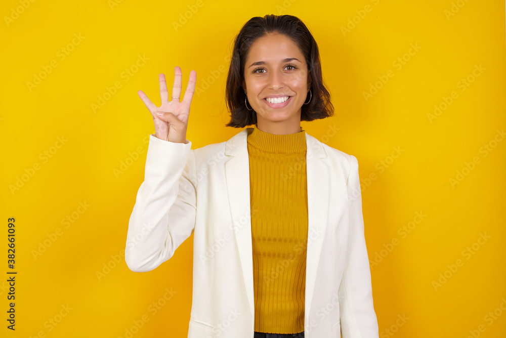 Young woman standing against gray wall showing and pointing up with fingers number four while smiling confident and happy. Young woman standing against gray wall showing and pointing up with fingers number four while smiling confident and happy.