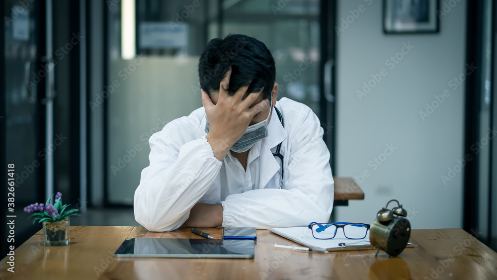 The picture of a doctor holding his head as he is thinking of a solution to the coronavirus COVID-19, with a tablet and Nalika on the table. The picture of a doctor holding his head as he is thinking of a solution to the coronavirus COVID-19, with a tablet and Nalika on the table.