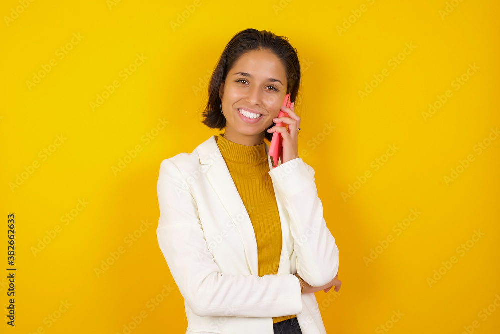 Portrait of a smiling young casual brunette woman talking on mobile phone isolated over white background. Portrait of a smiling young casual brunette woman talking on mobile phone isolated over white background.