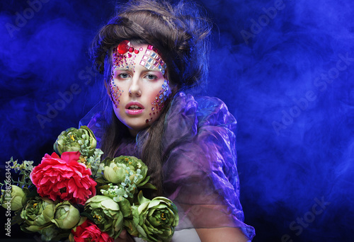 young woman with creative make up holding flowers