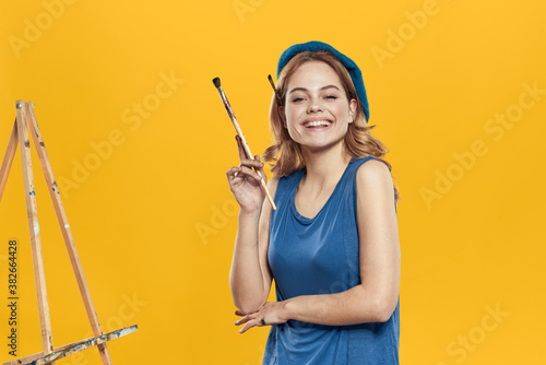 Artist woman in blue beret brush easel art drawing education hobby Creative approach yellow background