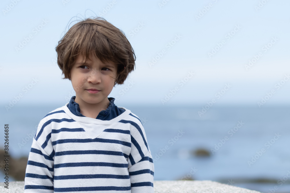 Portrait of a thoughtful little girl with the sea and the horizon out of focus in the background Portrait of a thoughtful little girl with the sea and the horizon out of focus in the background