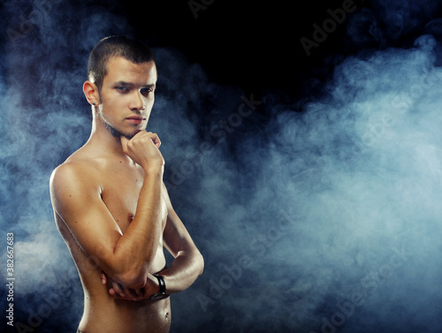 Portrait of a muscular male model against dark background with