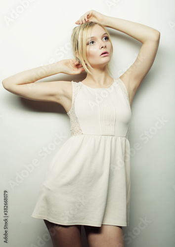 fashion blond woman in white dress posing in studio