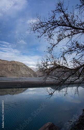 vertical landscape of shyok river with mirror reflections of mountains in cal water  photo