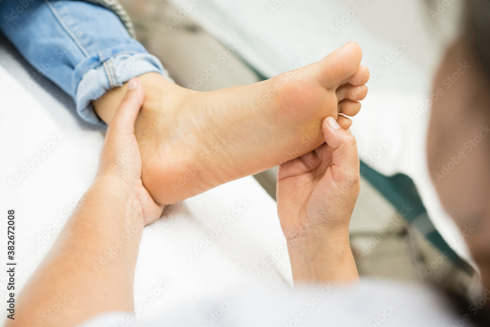 Reflexology, a massage used to relieve tension and treat illness. Hands pressing reflex points on the feet linked to different parts of the body.