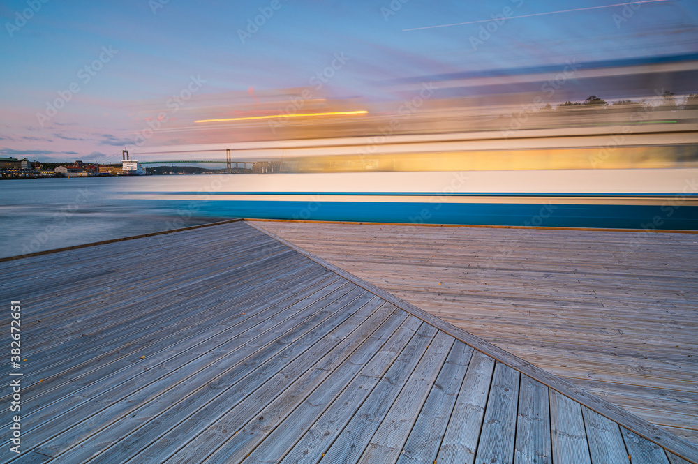 Ferry passing wooden pier at sunrise