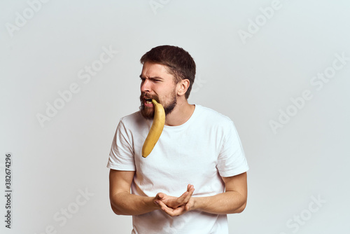 Cheerful man with a banana in his hands on a light background fun emotions Cropped view Copy Space
