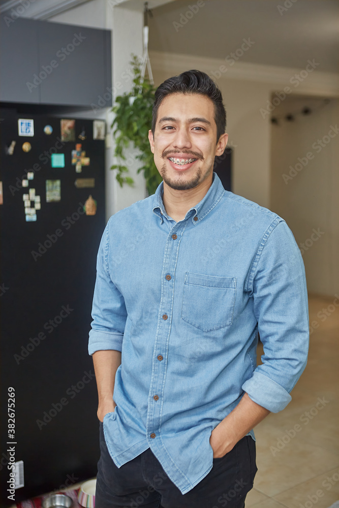 portrait of a hispanic young man with braces in the living room portrait of a hispanic young man with braces in the living room