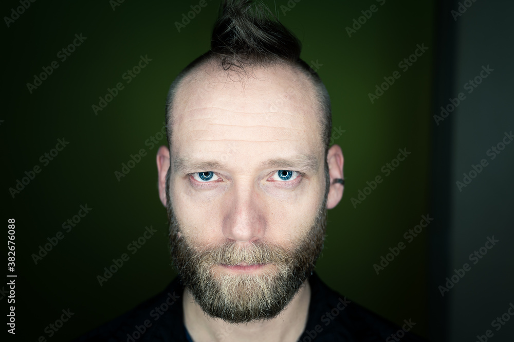 Fototapeta premium Man with beard and mohawk looks seriously at the camera.