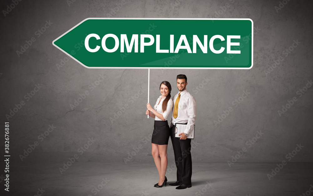 Young business person in casual holding road sign with COMPLIANCE inscription, new business direction concept Young business person in casual holding road sign with COMPLIANCE inscription, new business direction concept