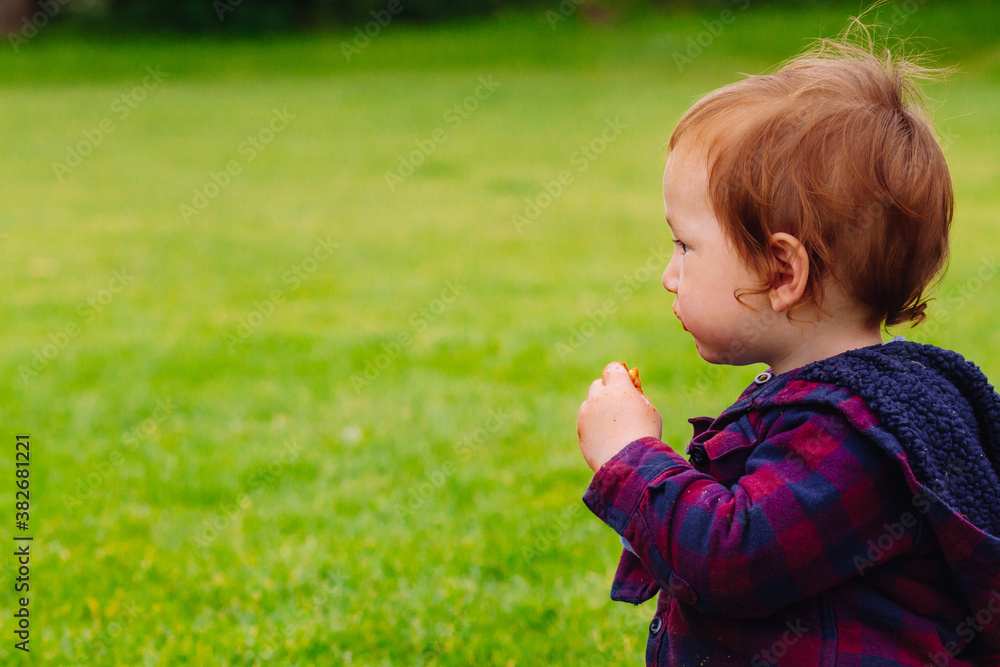 Child staring thoughtfully while holding a snack Child staring thoughtfully while holding a snack