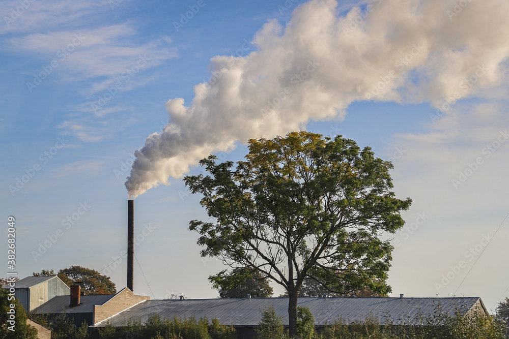 Smoke from chimney against a blue sky. Smoke chimney in an countryside environment Smoke from chimney against a blue sky. Smoke chimney in an countryside environment