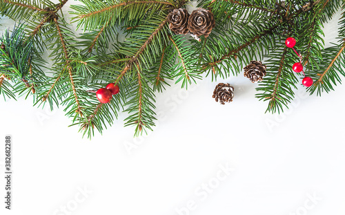 Christmas holiday greeting card. Fir branches decorated by berries and cones on white background. Space for text  flat lay