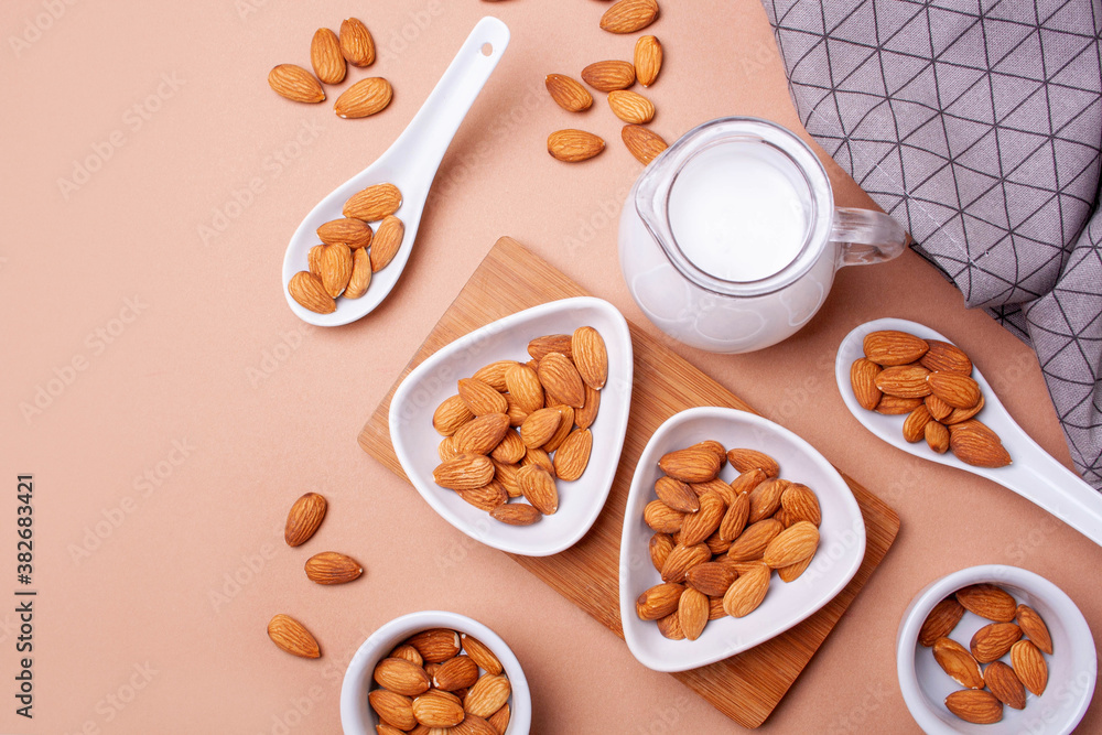 Decanter of almond milk and nuts on a beige background. Flat lay style Decanter of almond milk and nuts on a beige background. Flat lay style