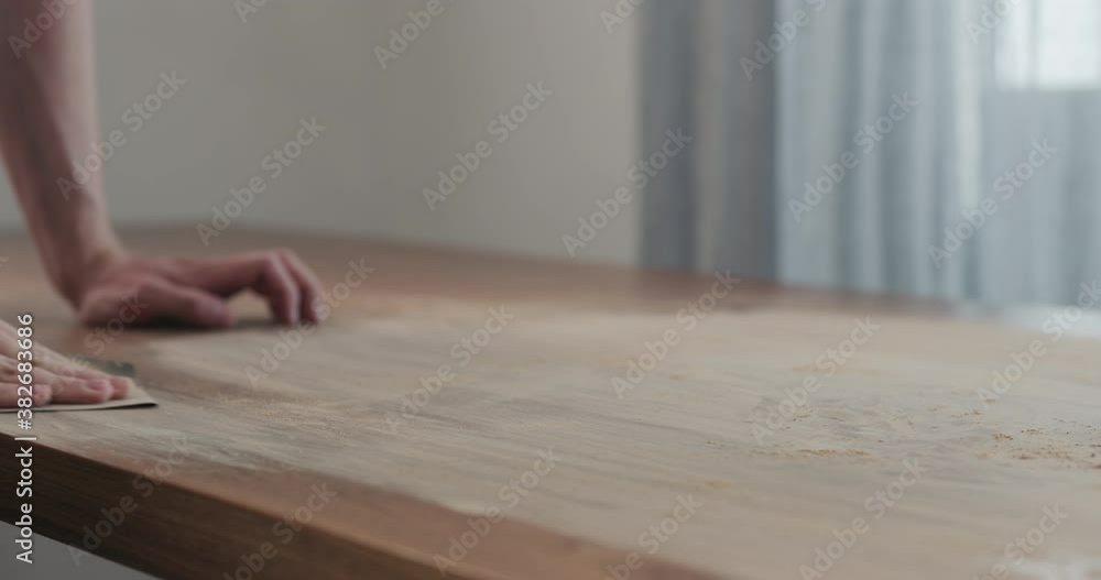 Slow motion slide orbit shot of man hand sanding black walnut wood table Slow motion slide orbit shot of man hand sanding black walnut wood table