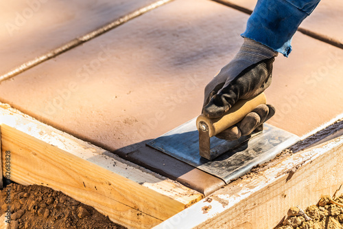 Vászonkép Construction Worker Using Hand Groover On Wet Cement Forming Coping Around New P