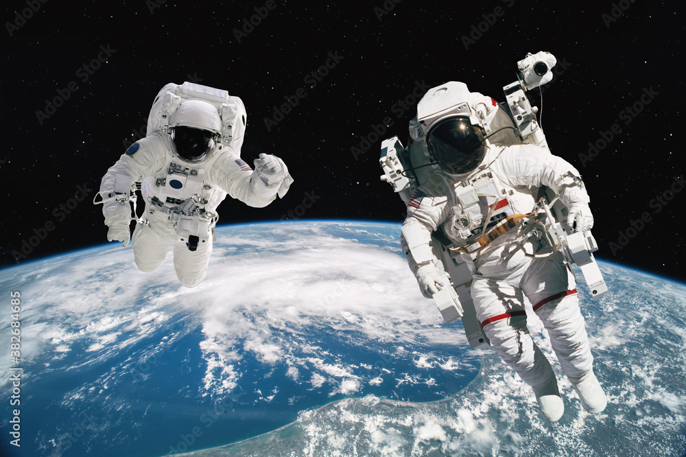 Two astronauts walking in space with earth background. Elements of this