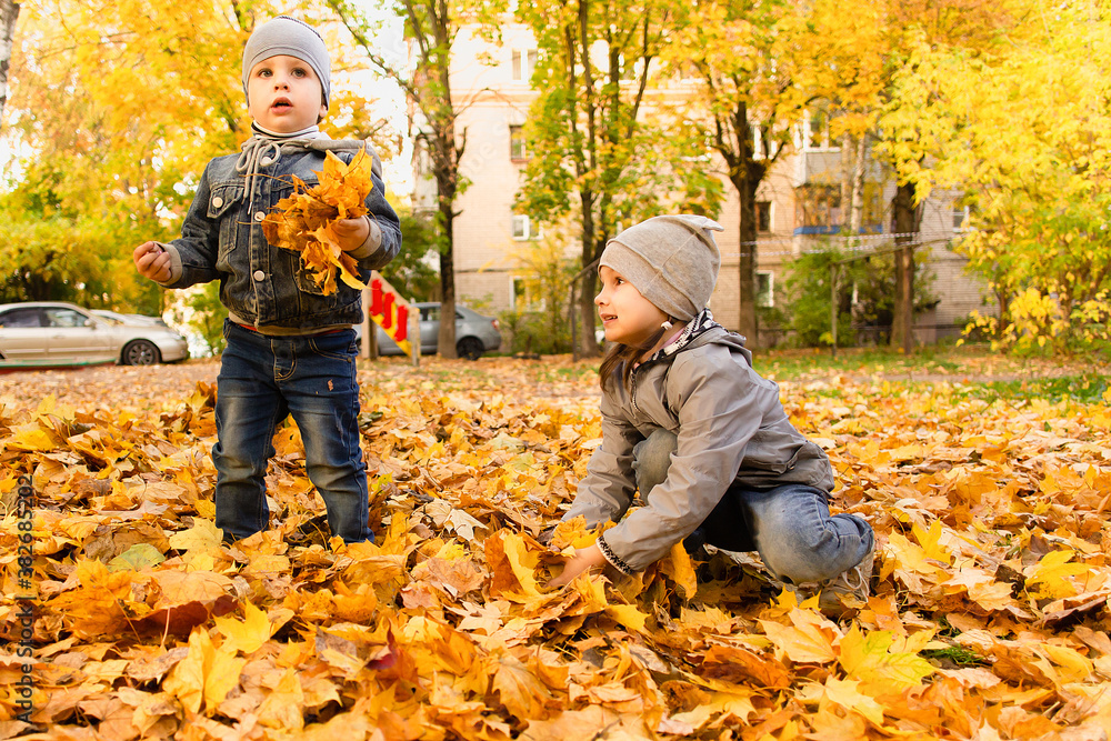 Happy boy and girl play in autumn foliage Happy boy and girl play in autumn foliage
