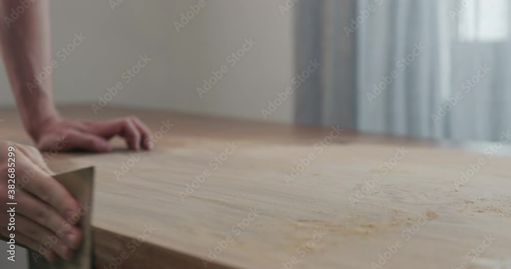 Slow motion slide orbit shot of man hand sanding black walnut wood table Slow motion slide orbit shot of man hand sanding black walnut wood table