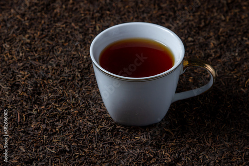 Leaf tea. a lot of loose tea. A cup of tea stands on loose tea