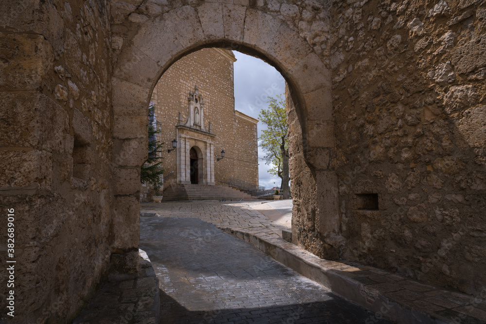 View of the main facade of the Church of Our Lady of the Assumption through the entrance portico to the church compound in Tarancón, Cuenca, Spain
