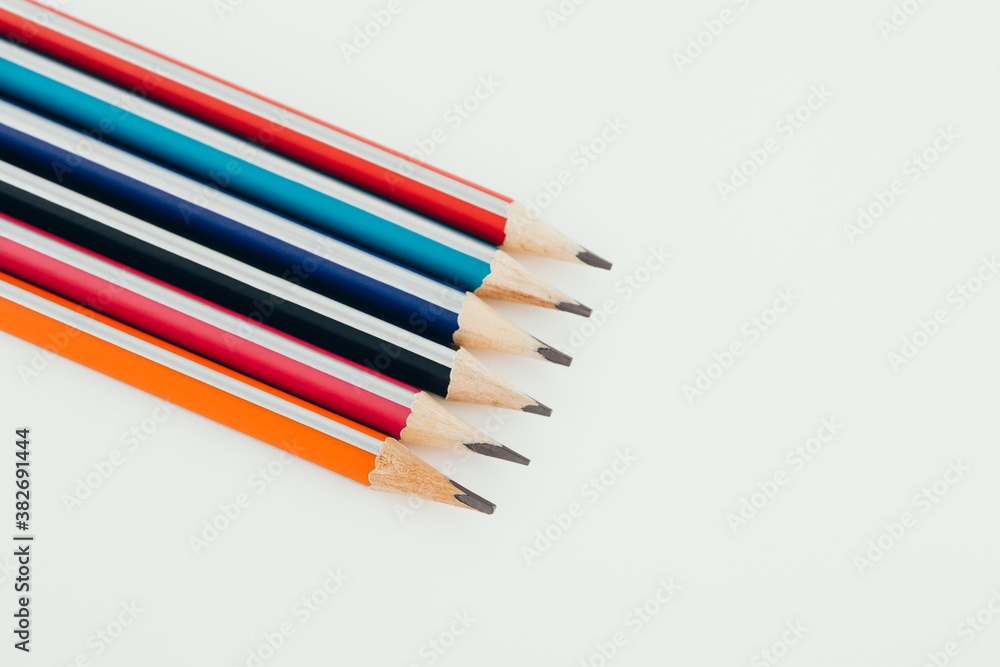 Multicolored wooden graphite pencils on light background. Top view. Multicolored wooden graphite pencils on light background. Top view.