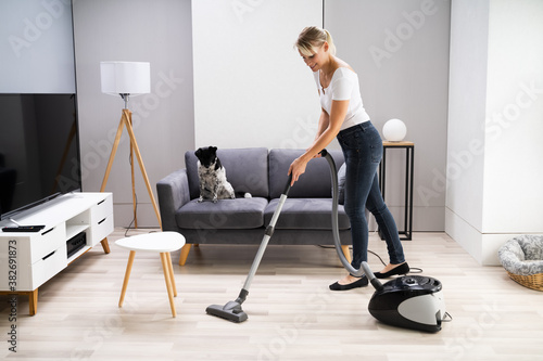 Young Maid Cleaning Carpet With Vacuum Cleaner