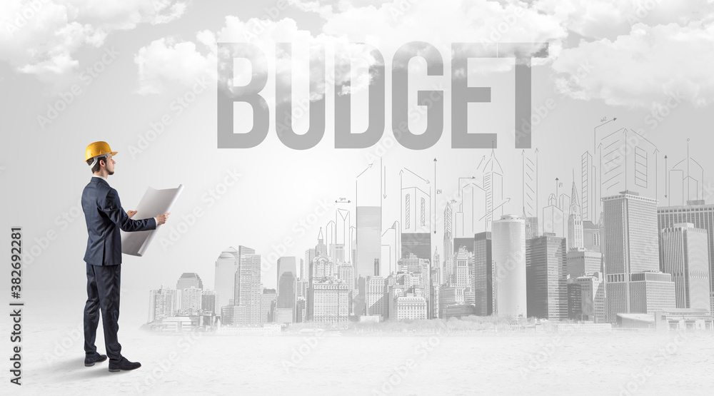 Young businessman with hard hat and BUDGET inscription, new business opportunity concept Young businessman with hard hat and BUDGET inscription, new business opportunity concept